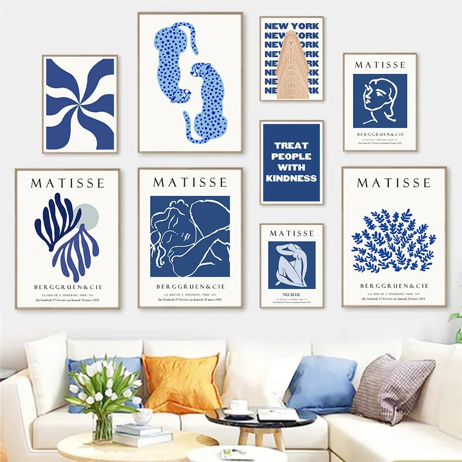 Neuf affiches bleues inspirées de Matisse (feuillages, nus, léopards, New York) au-dessus d’un canapé blanc