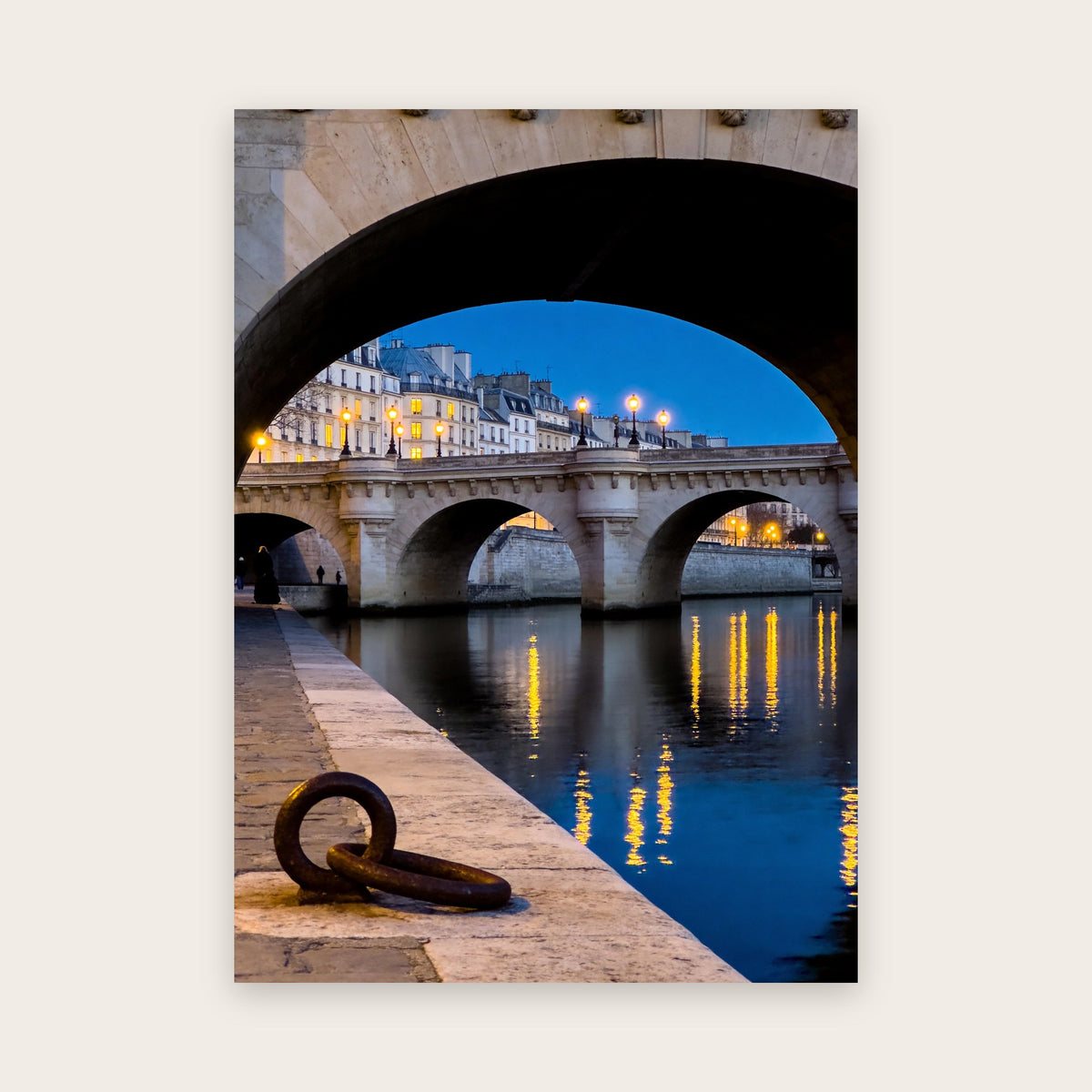 Affiche Paris à l'heure bleue : vieux pont de pierre aux arches éclairées vu sous une voûte, reflets dorés sur la Seine et anneau d'amarrage