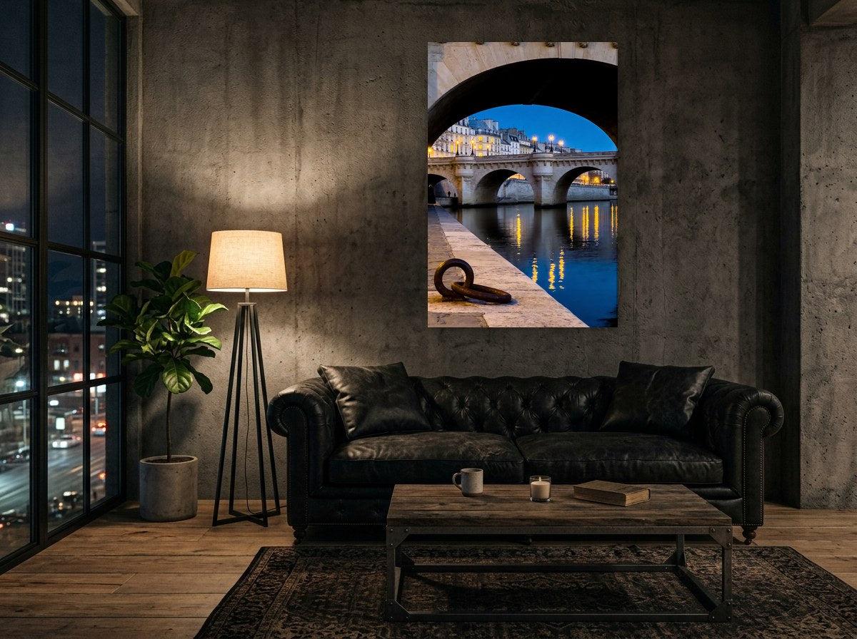Mise en situation : toile des arches sur la Seine au-dessus d'un canapé capitonné en cuir noir, contre un mur de béton brut dans un loft