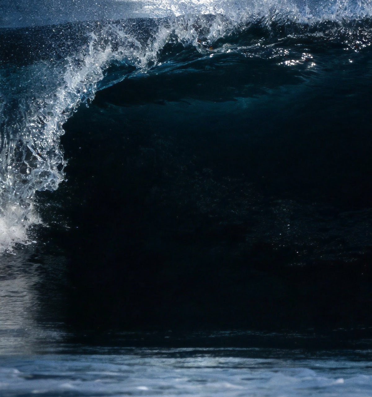 Détail : la crête argentée de la vague qui se brise et sa paroi bleu d'encre