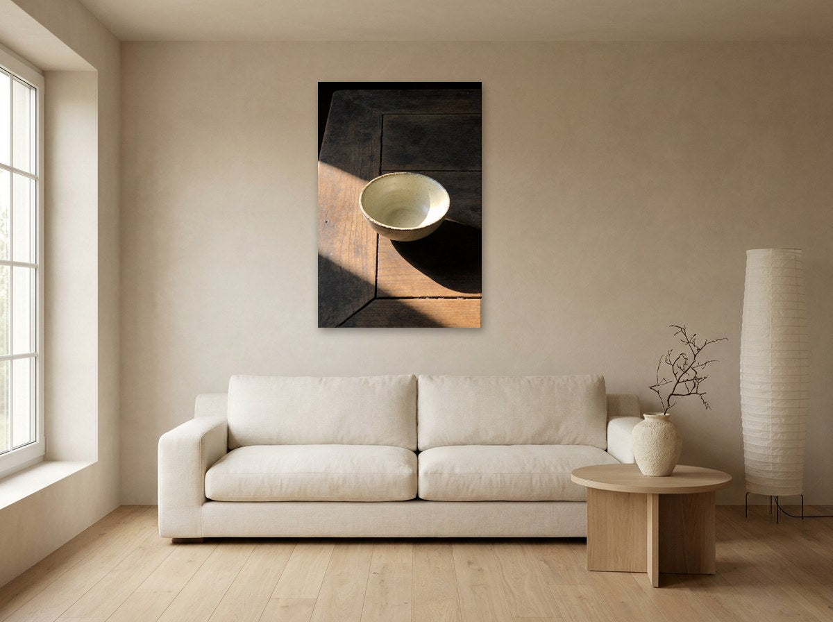 Mise en situation : toile « Bol et rai de lumière » au-dessus d'un canapé écru, sur le mur beige d'un salon japandi