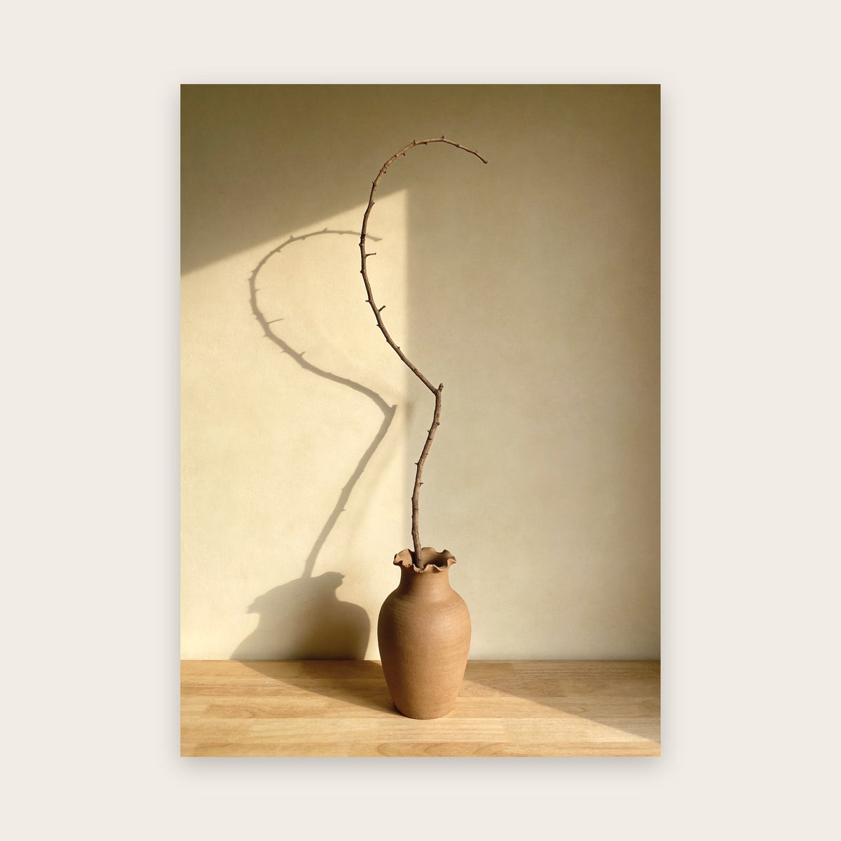 Affiche japandi au rendu photo : branche sèche dans un vase d’argile au col ondulé, ombres portées sur un mur ivoire, plateau de bois clair