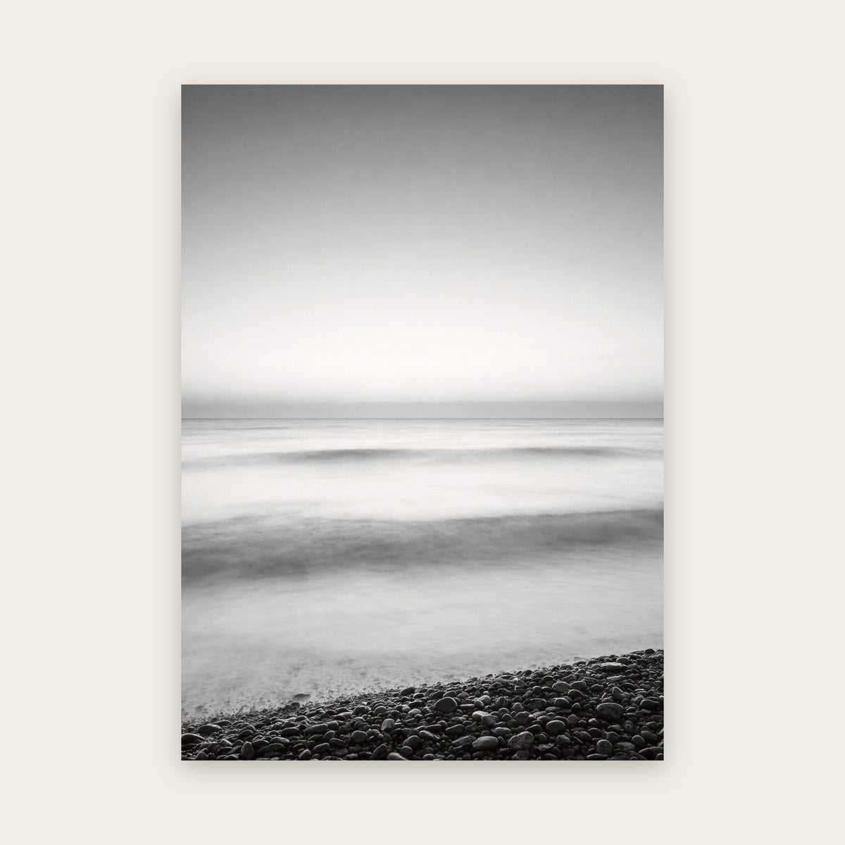 Affiche mer noir et blanc minimaliste : vagues adoucies en brume par une pose longue sur une plage de galets, grand ciel pâle