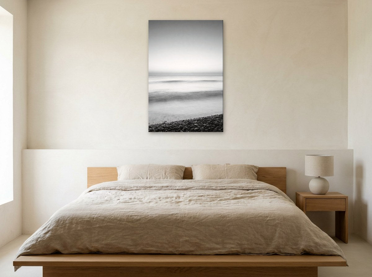 Mise en situation : toile « Brume d'aube sur les galets » au-dessus d'un lit en lin beige, dans une chambre aux murs crème