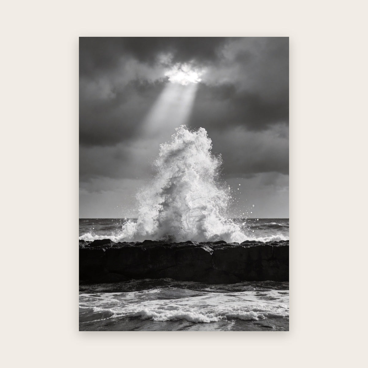 Affiche vague noir et blanc : gerbe d'écume qui jaillit derrière une roche plate sous un rayon de lumière perçant un ciel d'orage