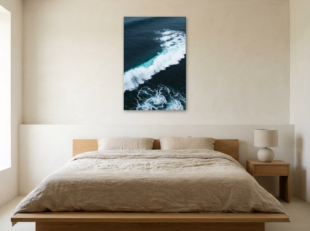 Mise en situation : toile « Dentelle d'écume vue du ciel » au-dessus d'un lit en lin beige, dans une chambre aux murs crème