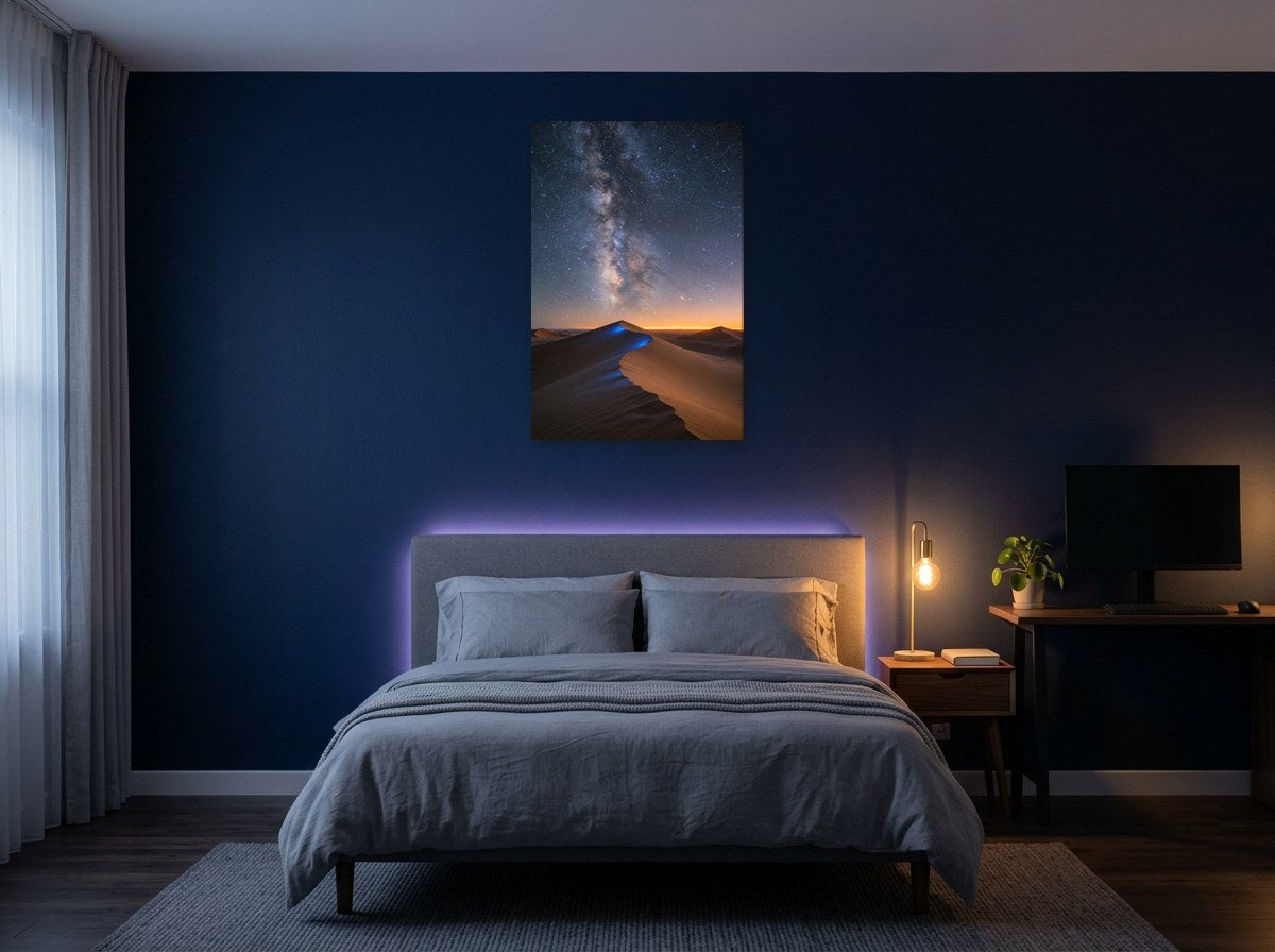 Mise en situation : toile « Dunes sous la Voie lactée » au-dessus d'un lit aux draps gris, sur le mur bleu nuit d'une chambre éclairée par une lampe de chevet
