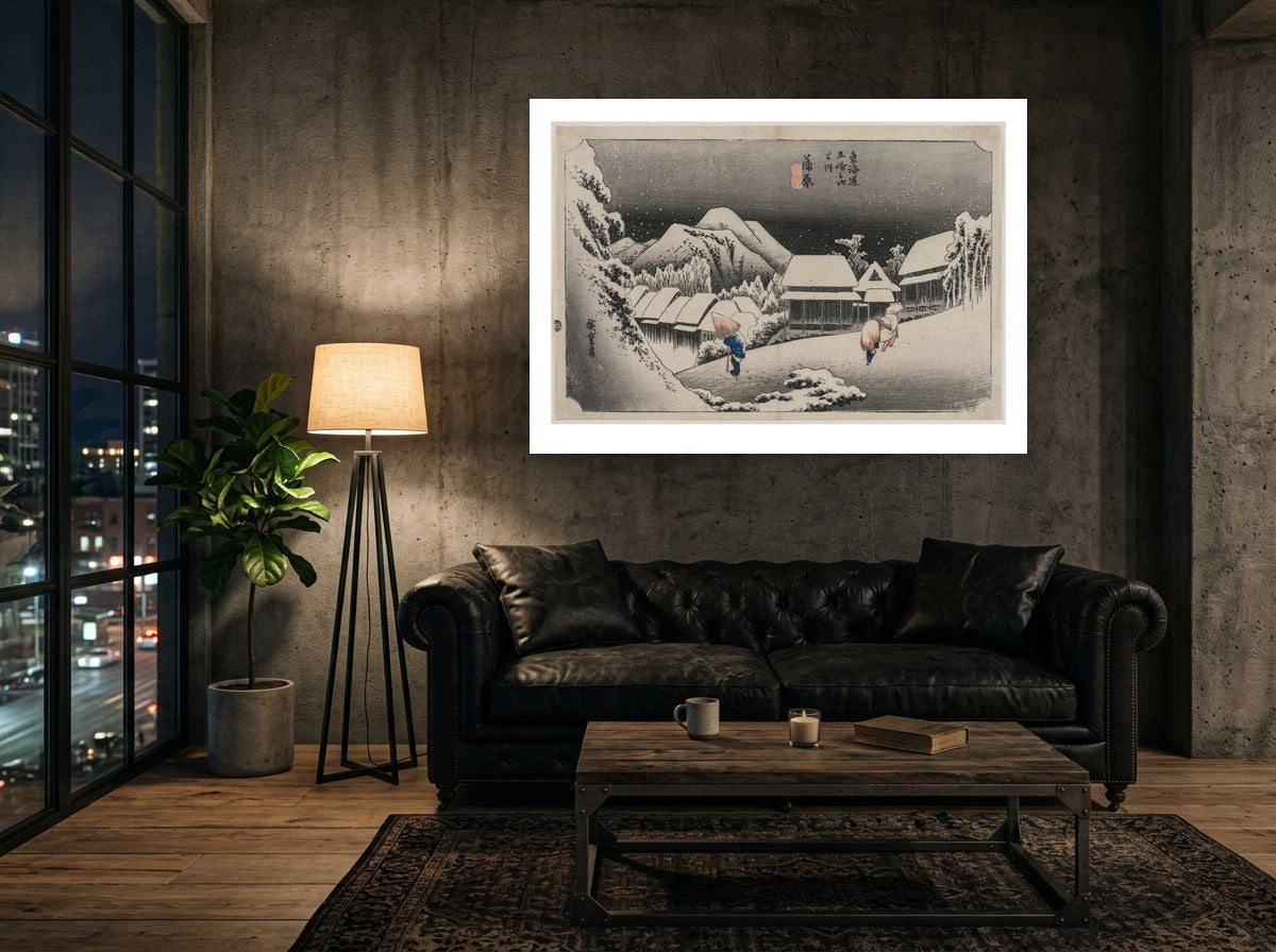 Mise en situation : affiche Nuit de neige à Kambara au mur en béton brut d'un loft, au-dessus d'un canapé Chesterfield noir