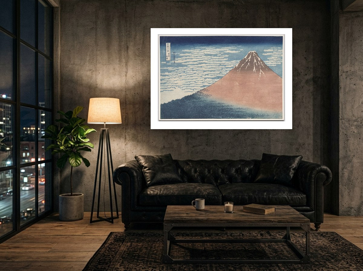 Mise en situation : affiche Le Fuji rouge au mur de béton brut d'un loft, au-dessus d'un canapé Chesterfield en cuir noir