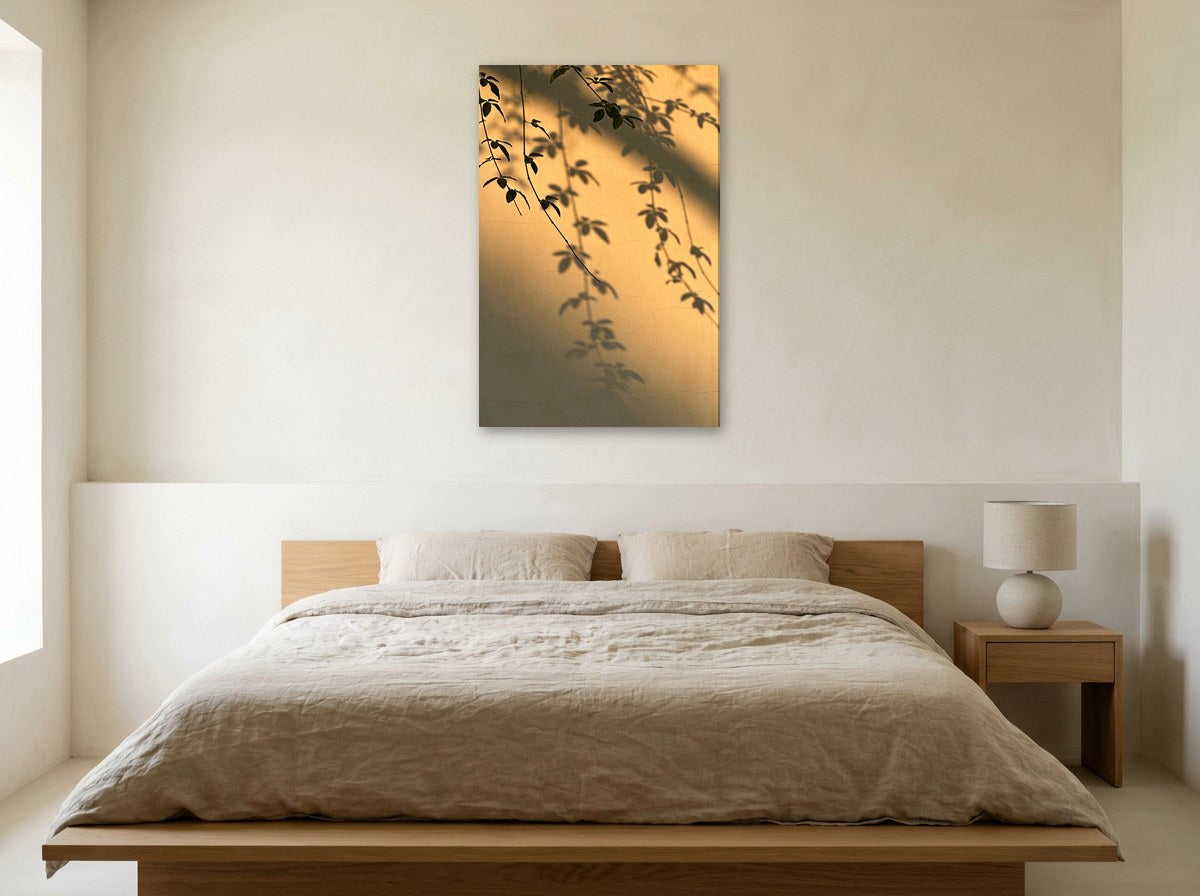 Mise en situation : toile « Ombres de feuillage » au-dessus d'un lit en lin beige, dans une chambre aux murs crème