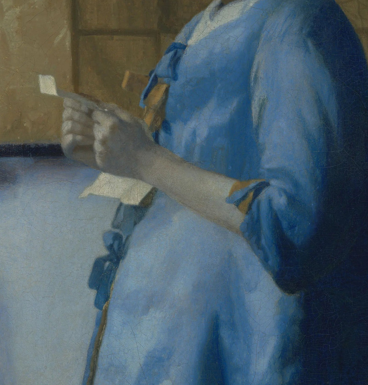Détail de La Femme en bleu lisant une lettre (Vermeer) : mains tenant la lettre, veste bleue à nœuds, carte ocre au mur